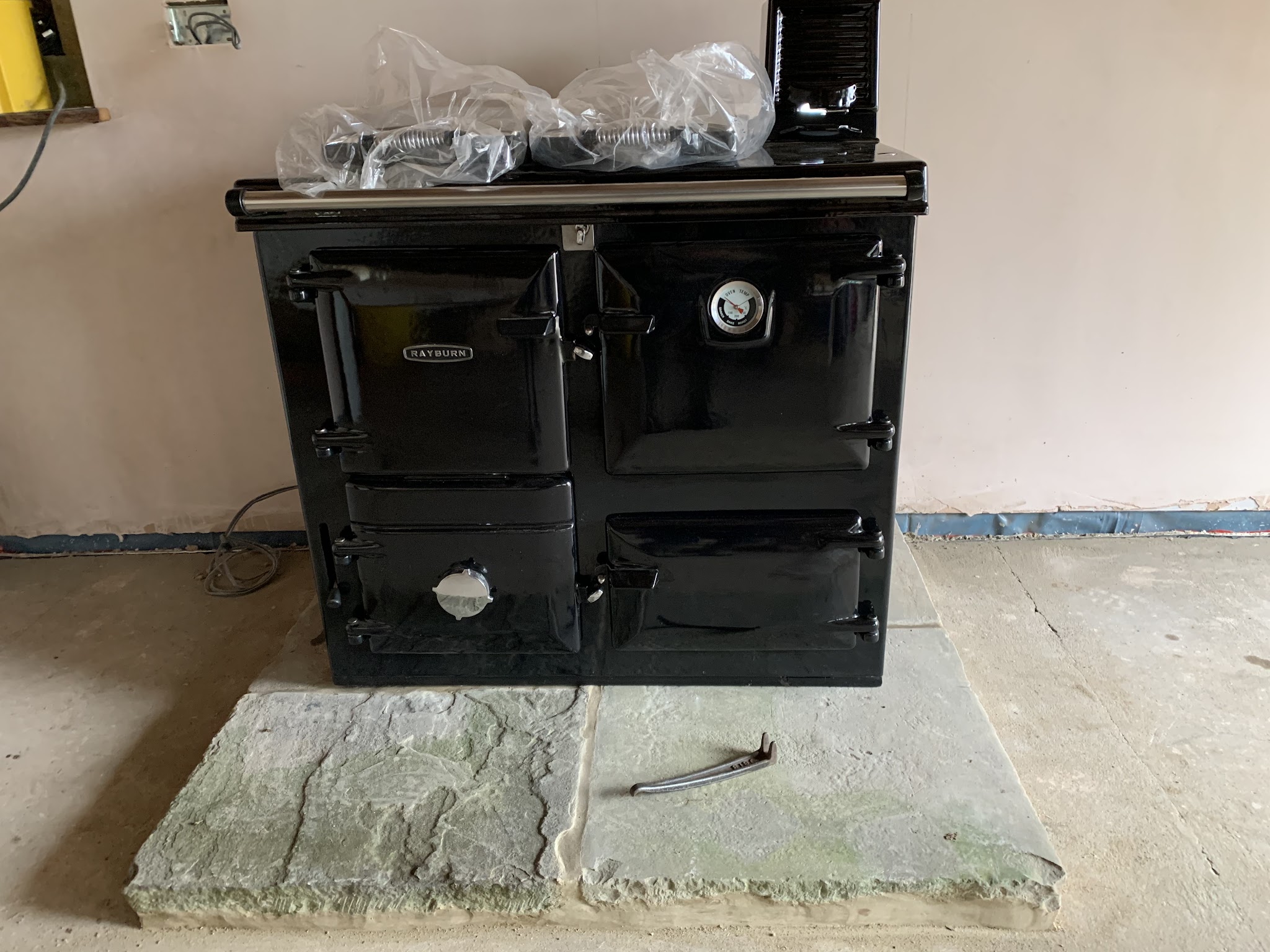 A black range cooker set on a new stone hearth during installation