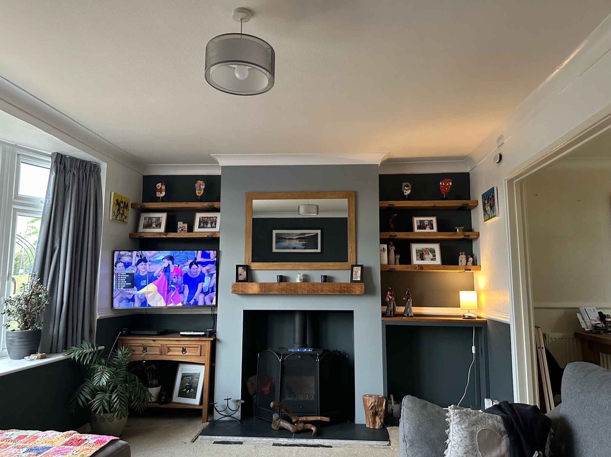 A living room with a stove in a dark recess beneath an oak mantel