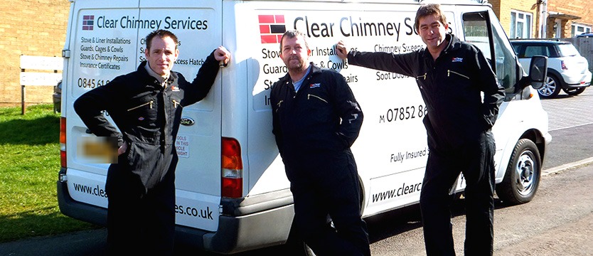 Three of the Clear Chimney Services team in branded overalls beside the company van